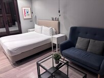 Queen bed and sitting area facing large TV