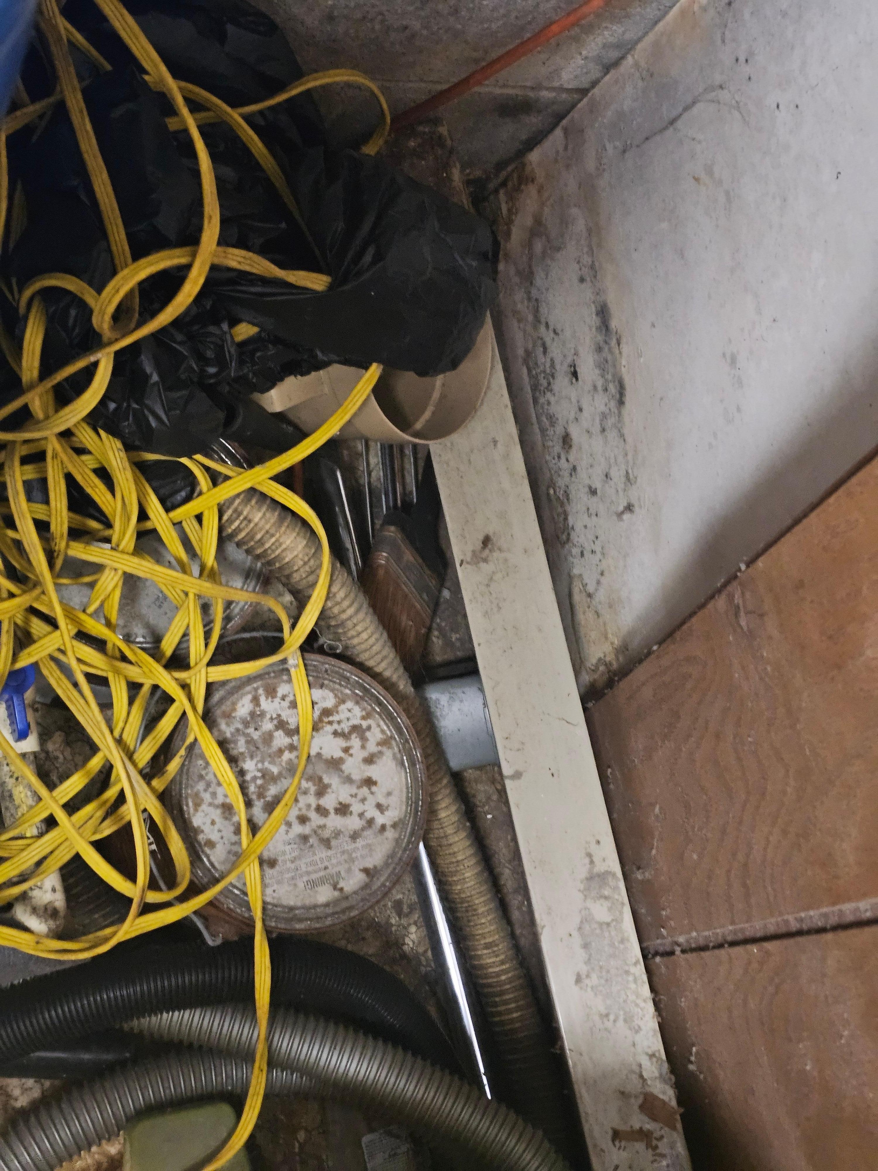 Electric baseboard heater peeled off the wall by paneling and is covered up by items.