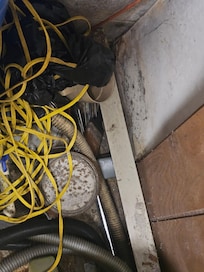 Electric baseboard heater peeled off the wall by paneling and is covered up by items.