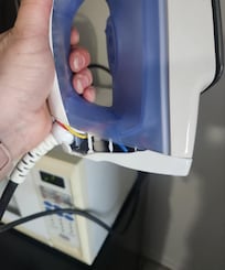 Clothes iron with piece broken off and exposed wiring
