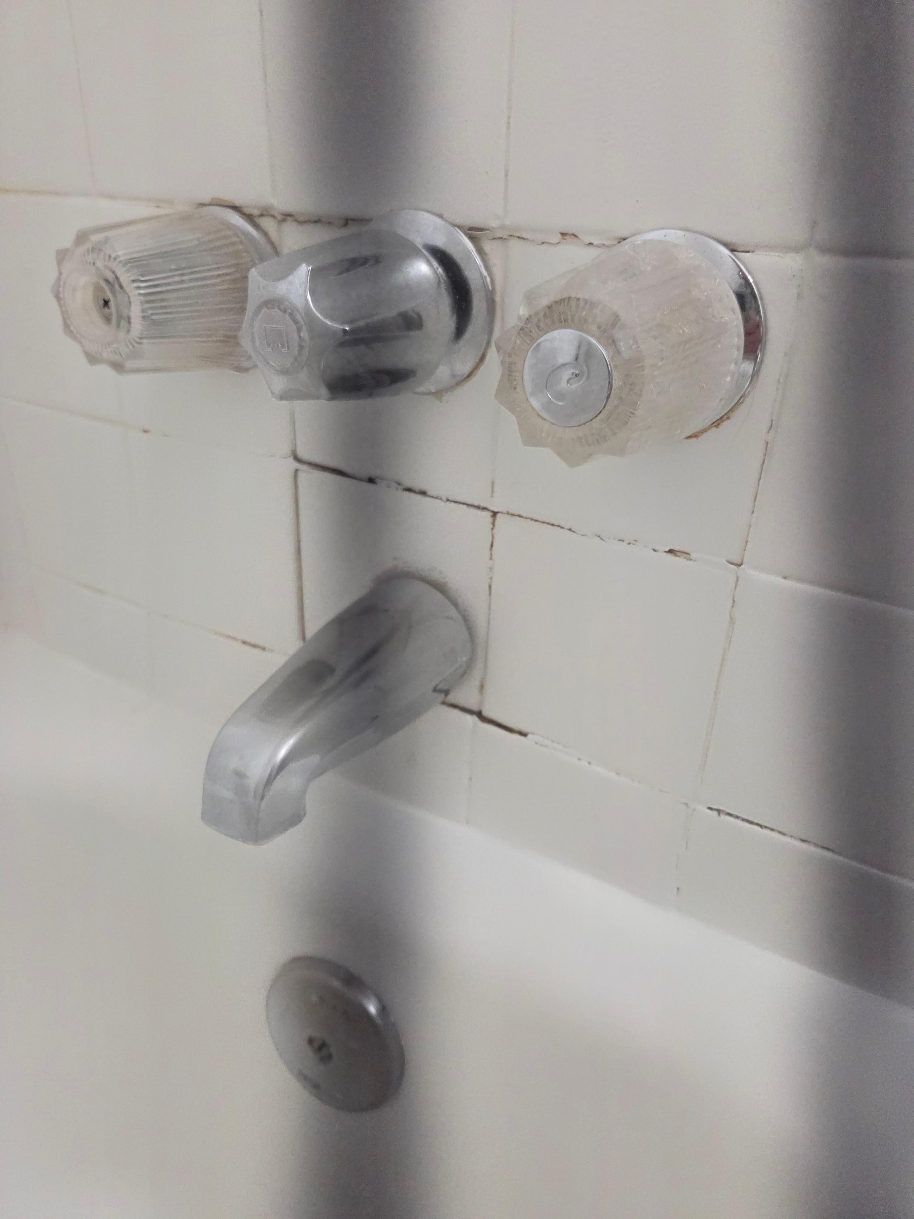 Wall by bathtub faucet. 