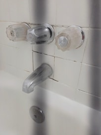 Wall by bathtub faucet.