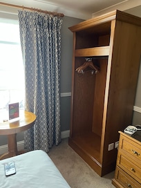 Cramped bed area with table and chair blocking that side of the bed