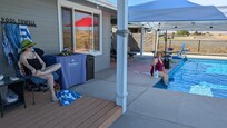 My daughters relaxing poolside. The reflection in the window shows the view out the back.