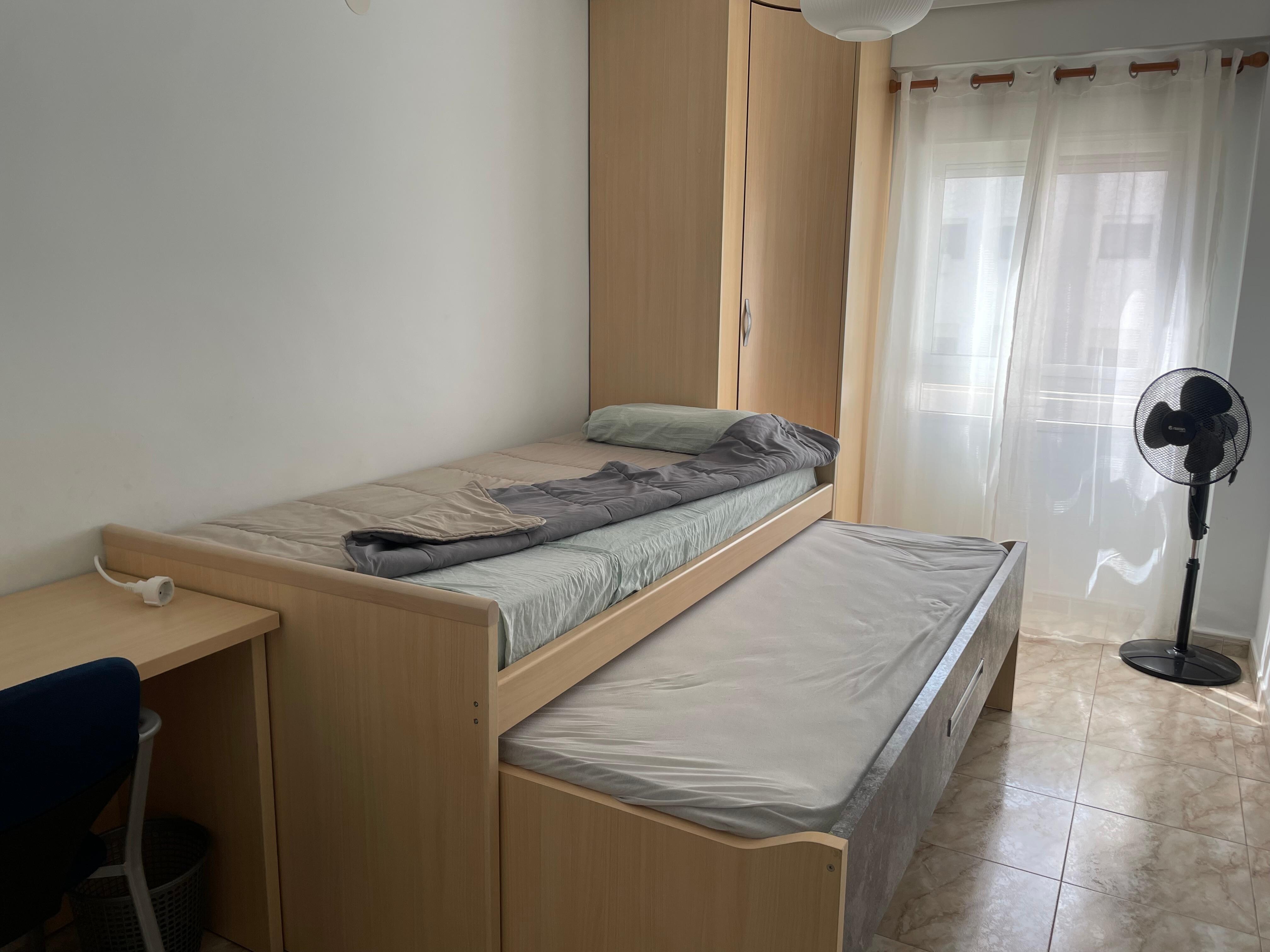 Bedroom with 2 beds. There’s also a table and chairs and clotheslines outside the window.