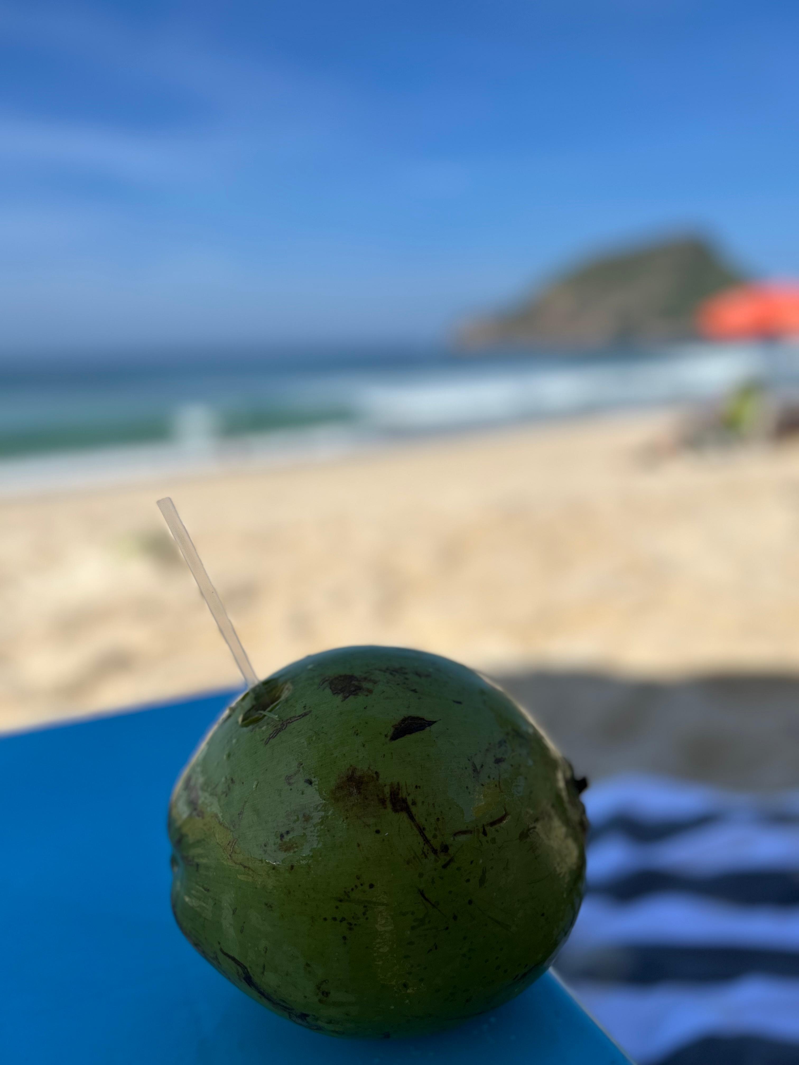 Desfrutando água de côco na praia com a sombra da barraca fornecida pelo hotel