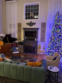 Family room, sky high ceiling, piano, fireplace, television, comfy couches and chairs. Just off the dining room and with a doors leading to the backyard .