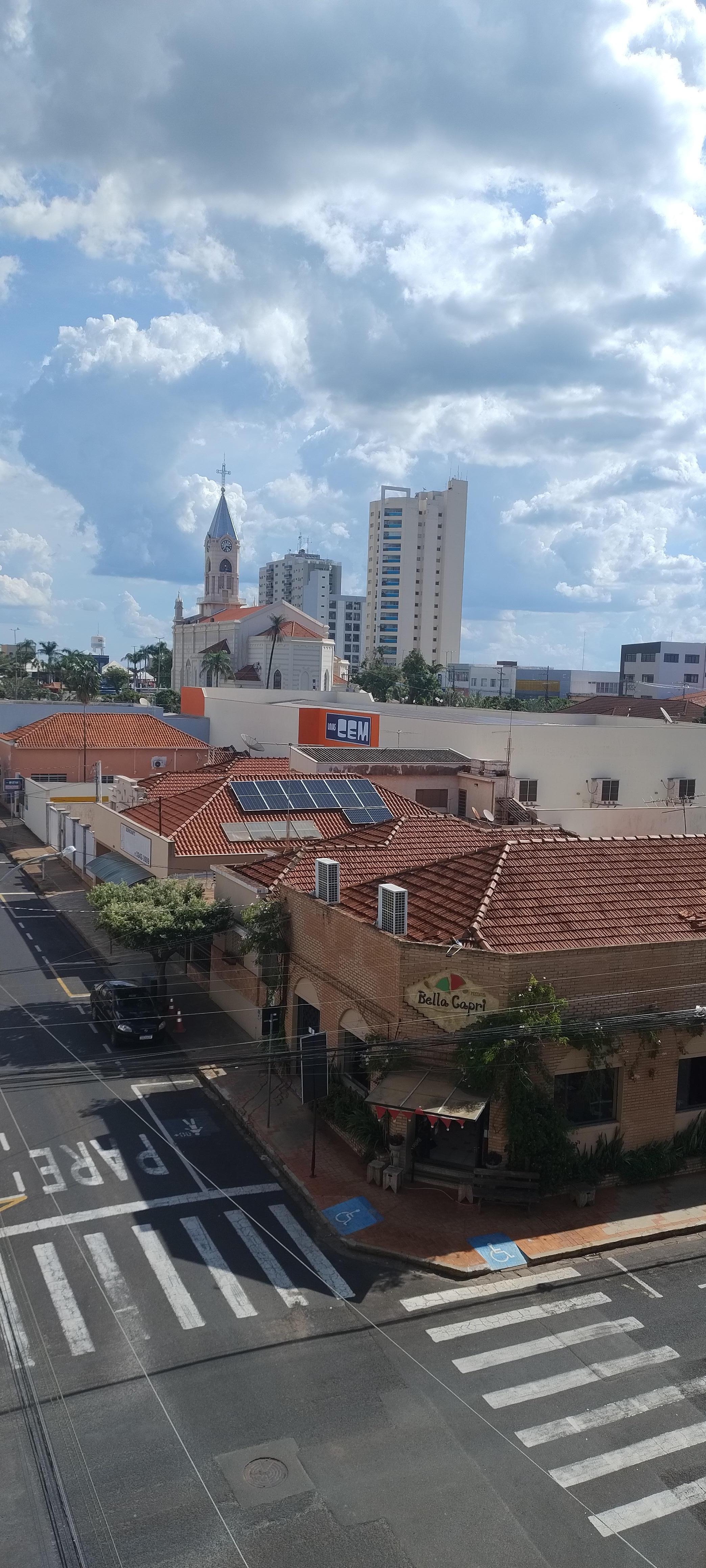 Visual da janela, com torre da igreja aparecendo na praça central 