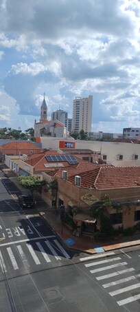 Visual da janela, com torre da igreja aparecendo na praça central