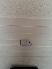 Unsafe electrical outlets set within a wooden panel