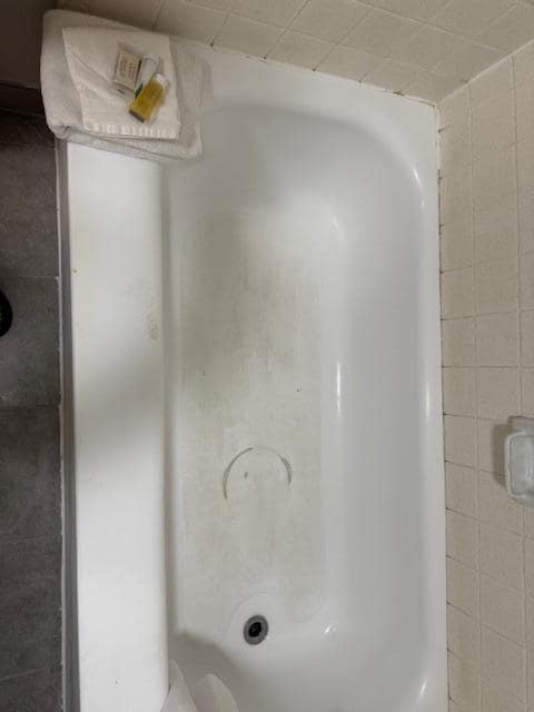 Filthy tub bottom and lots of black mold along edge of tub with wall.