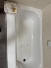 Filthy tub bottom and lots of black mold along edge of tub with wall.