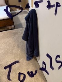 Dirty towels hanging on a door knob with one of the bedrooms