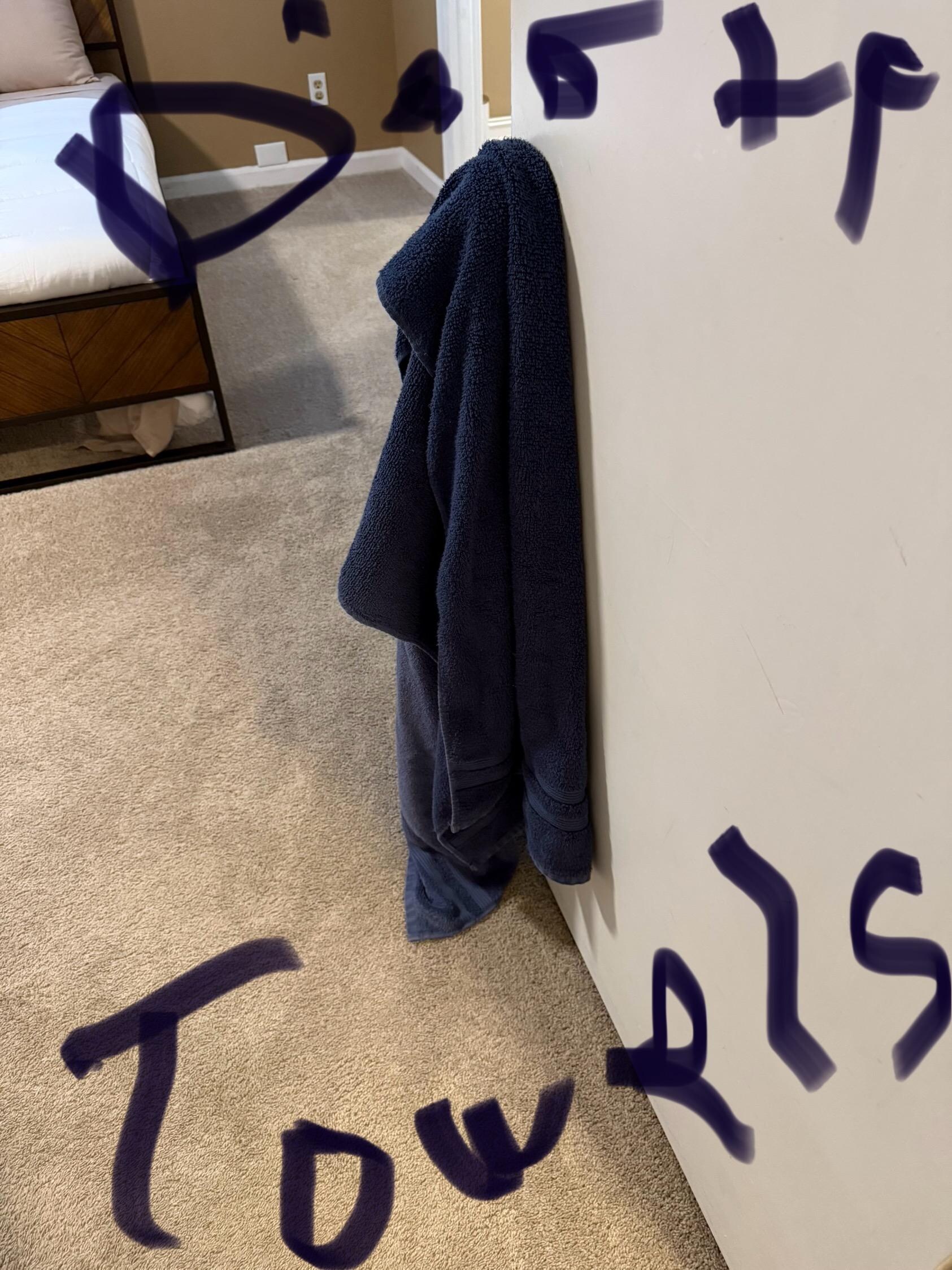 Dirty towels hanging on a door knob with one of the bedrooms