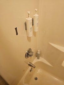 Shower with broken amenity and hair/dust on shelves