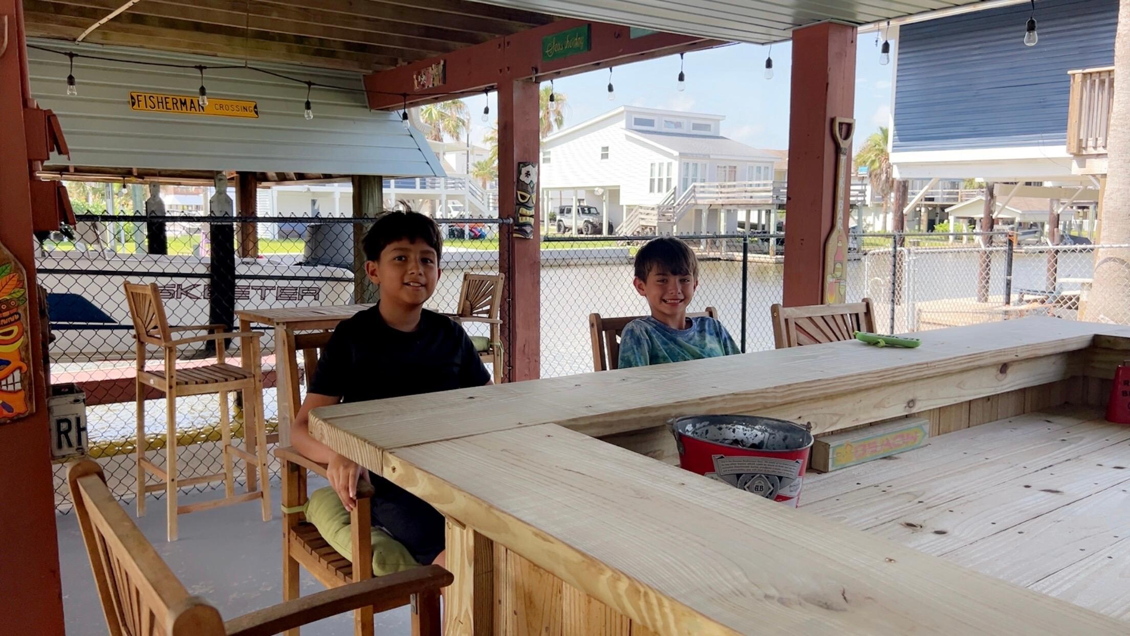 The boys sitting at the counter area watching tv on the downstairs patio