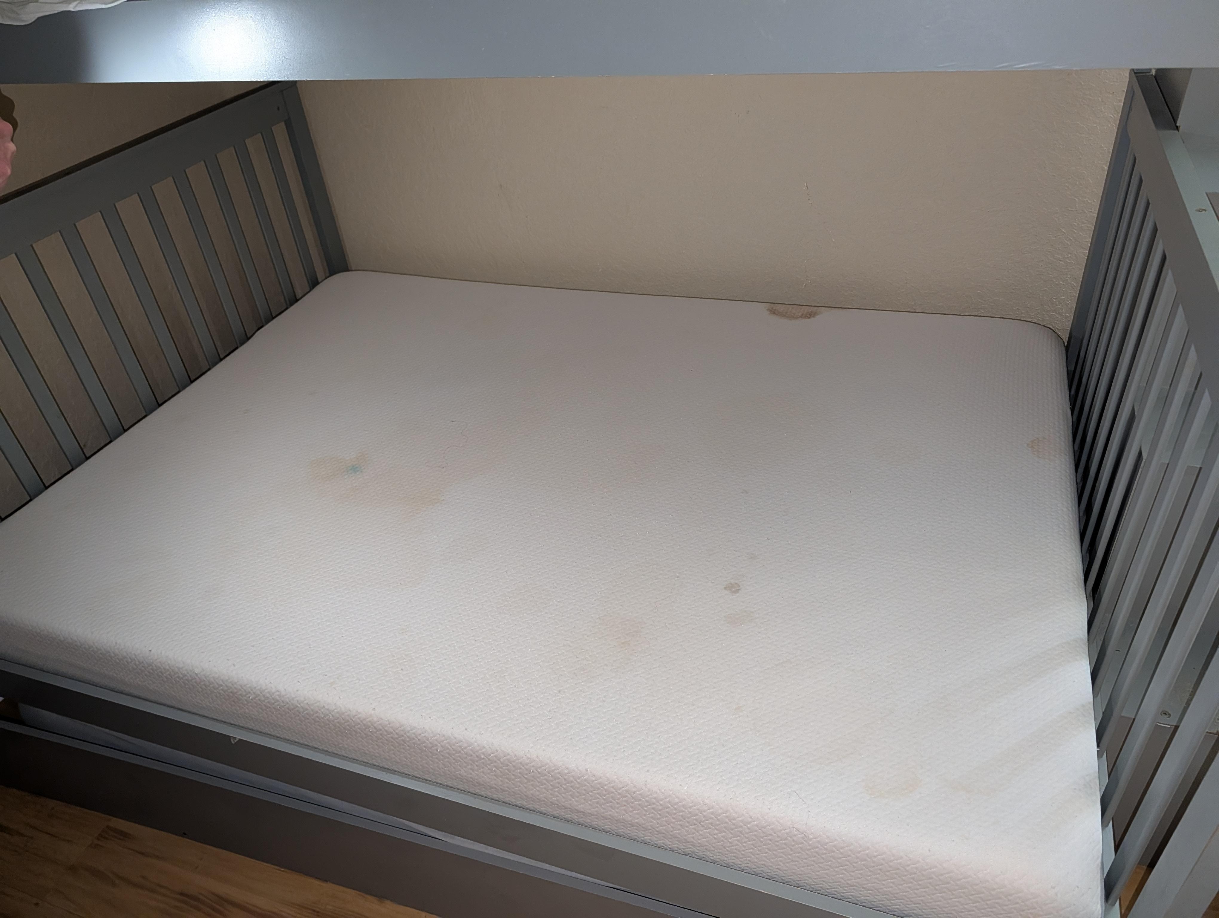 Stained mattress protector found on the bunk bed. While one stain was fresh and smelled strongly of urine, the others show accumulated grime and neglect. It was clear this had not been properly laundered in months