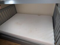 Stained mattress protector found on the bunk bed. While one stain was fresh and smelled strongly of urine, the others show accumulated grime and neglect. It was clear this had not been properly laundered in months