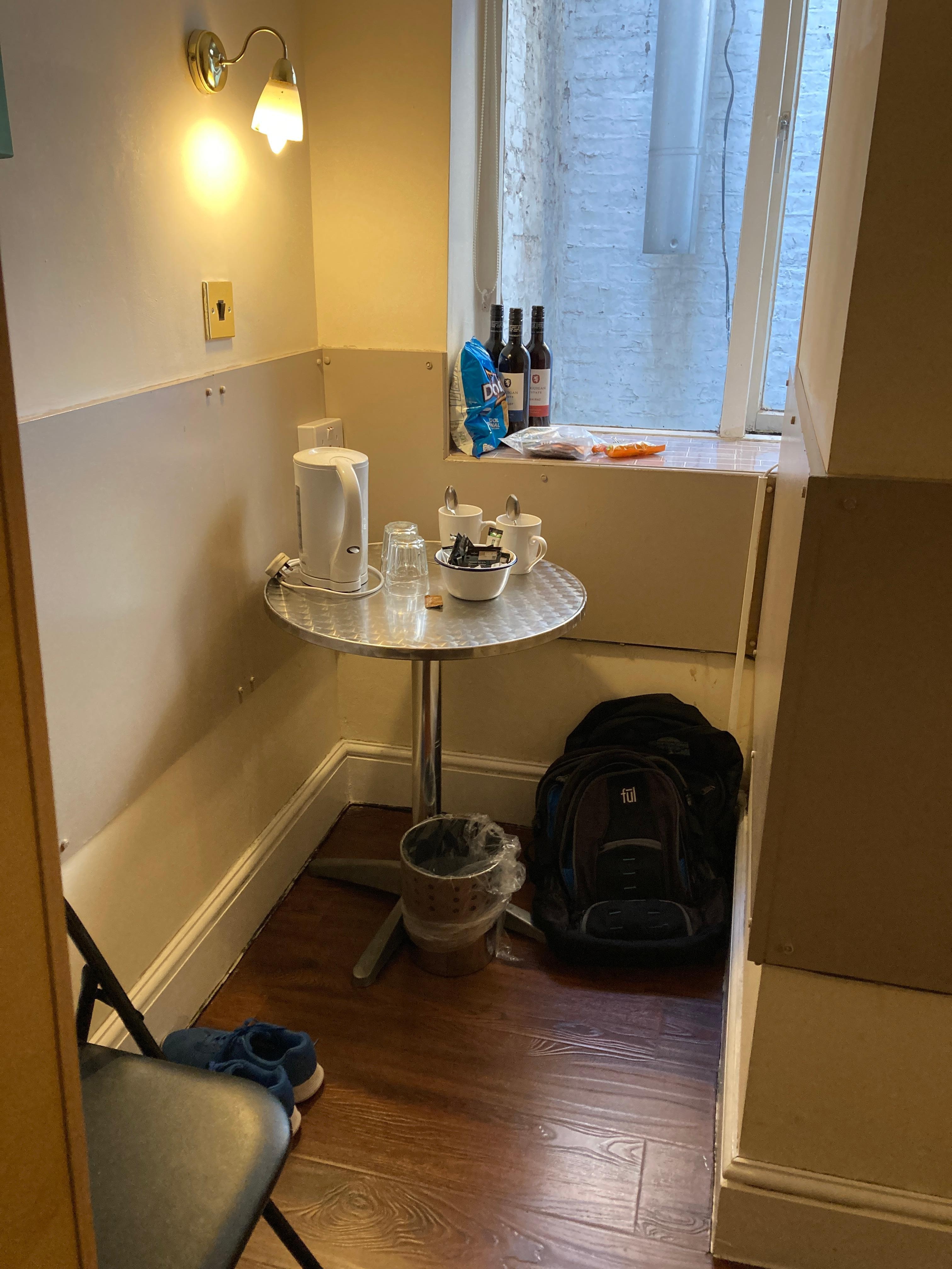 Alcove with table, hot water pot, instant coffee & tea, and one small folding chair in the room