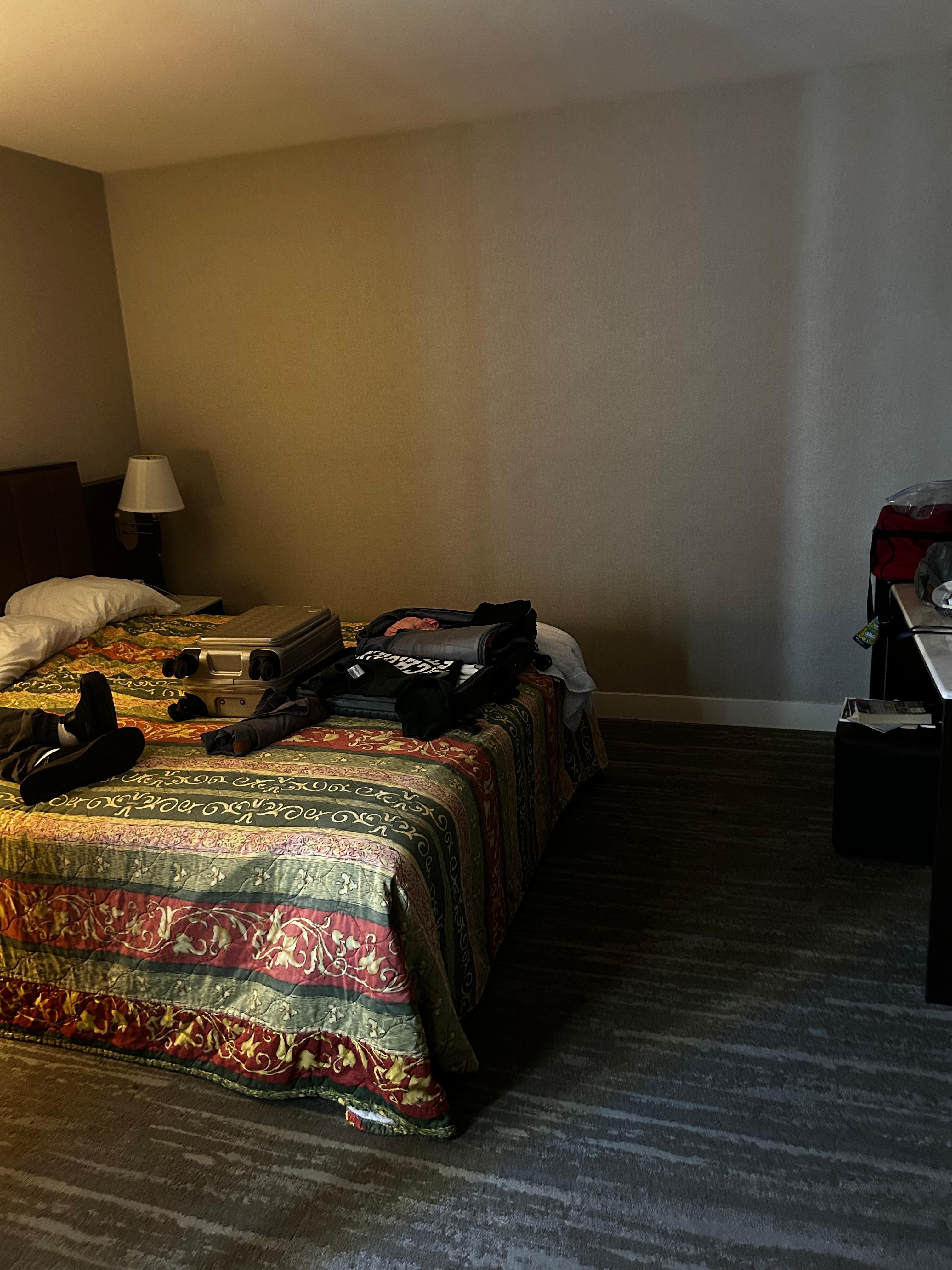 Bed facing tv with remote and counter space with two stools. 