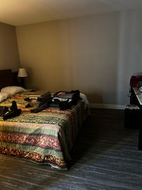 Bed facing tv with remote and counter space with two stools.