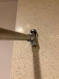 Broken shower rod that was hanging off the wall for its dear life