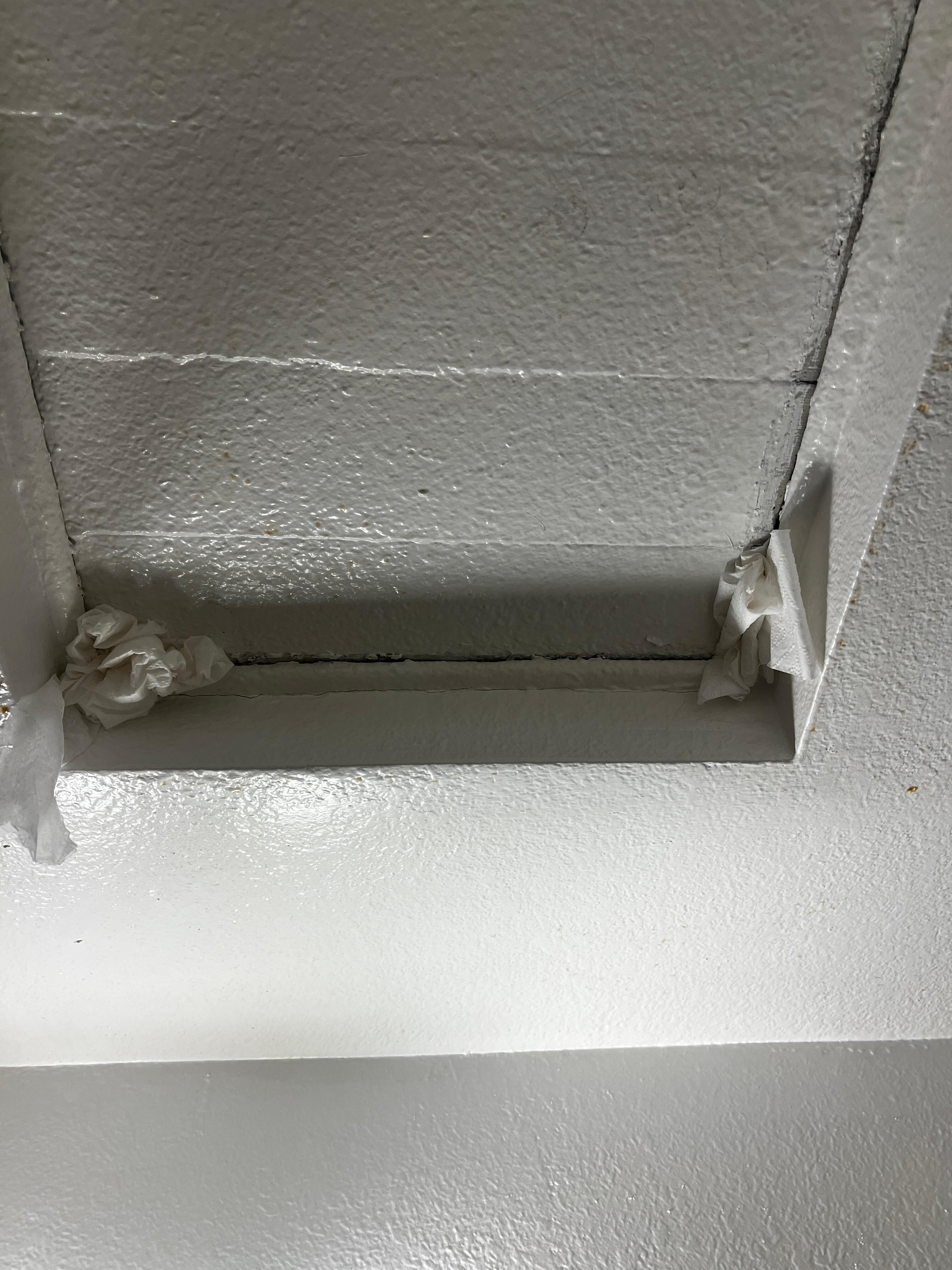 Toilette paper shoved in trapdoor in ceiling.