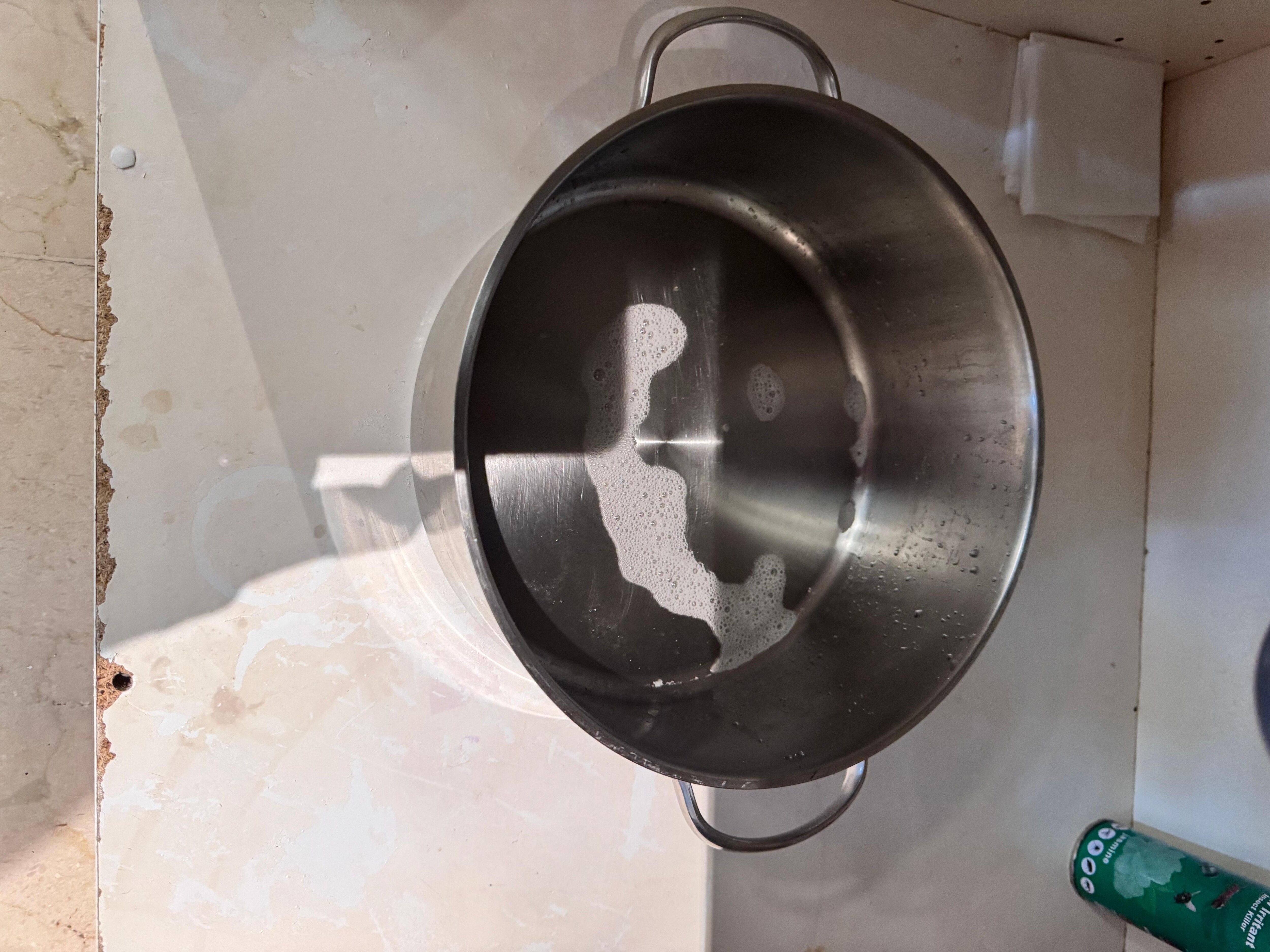 Pan placed underneath sink to catch leaking water (smelled musty so probably an active leaks for some time)
