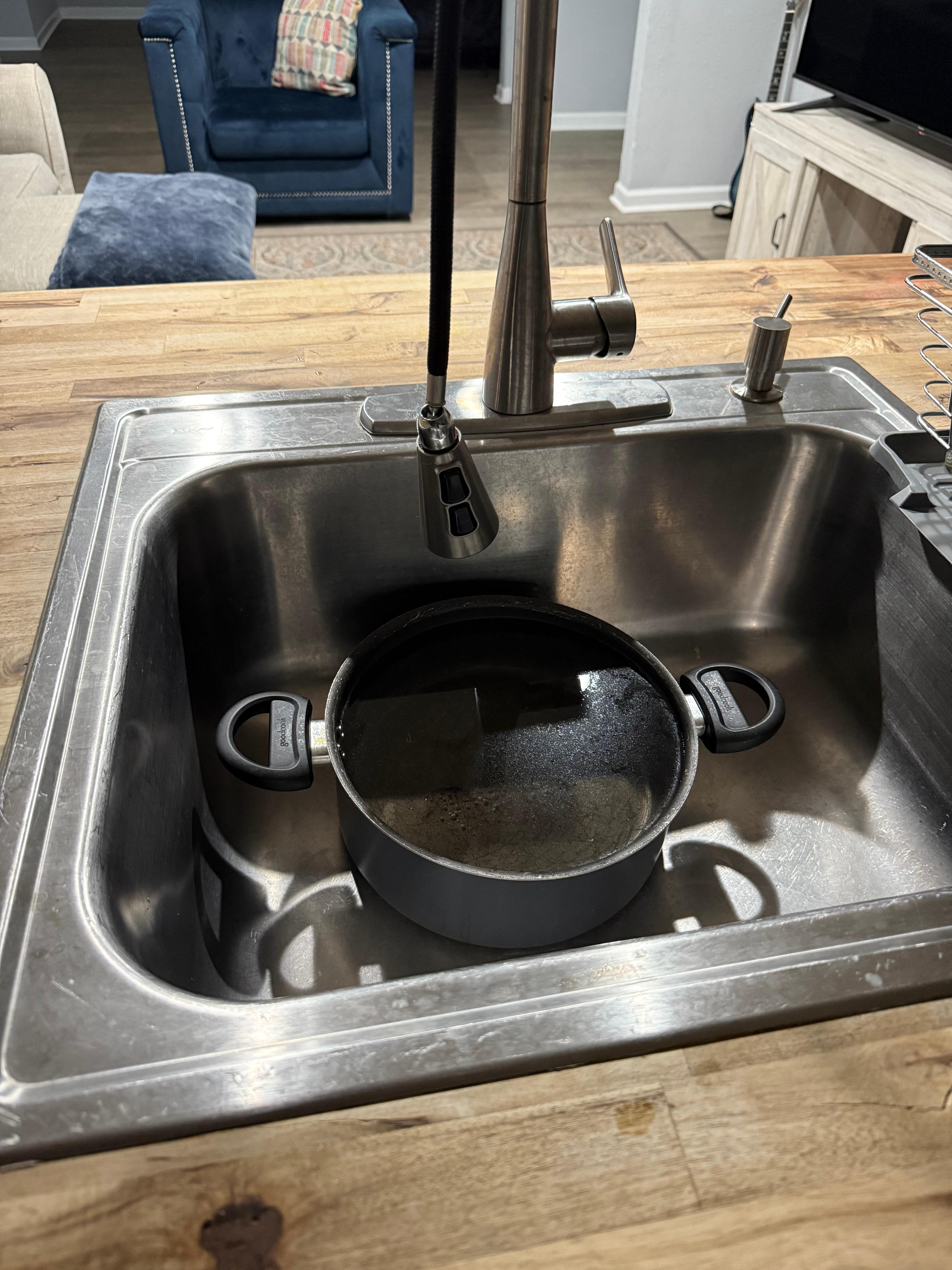 This is a picture of the dirty pot in sink and the broken faucet hanging down. 