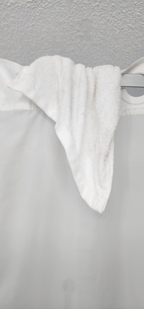 Used hairy washcloth hanging over shower rod
