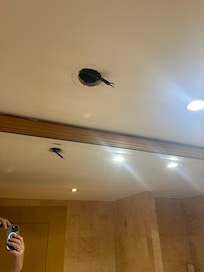 Live uncapped wires hanging from the washroom ceiling.