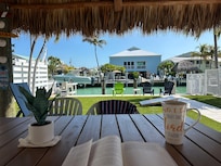 View of backyard and canal from outdoor dining table (under tiki)