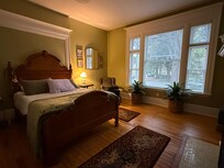 Bedroom with fireplace and beautiful windows looking out on pretty street.