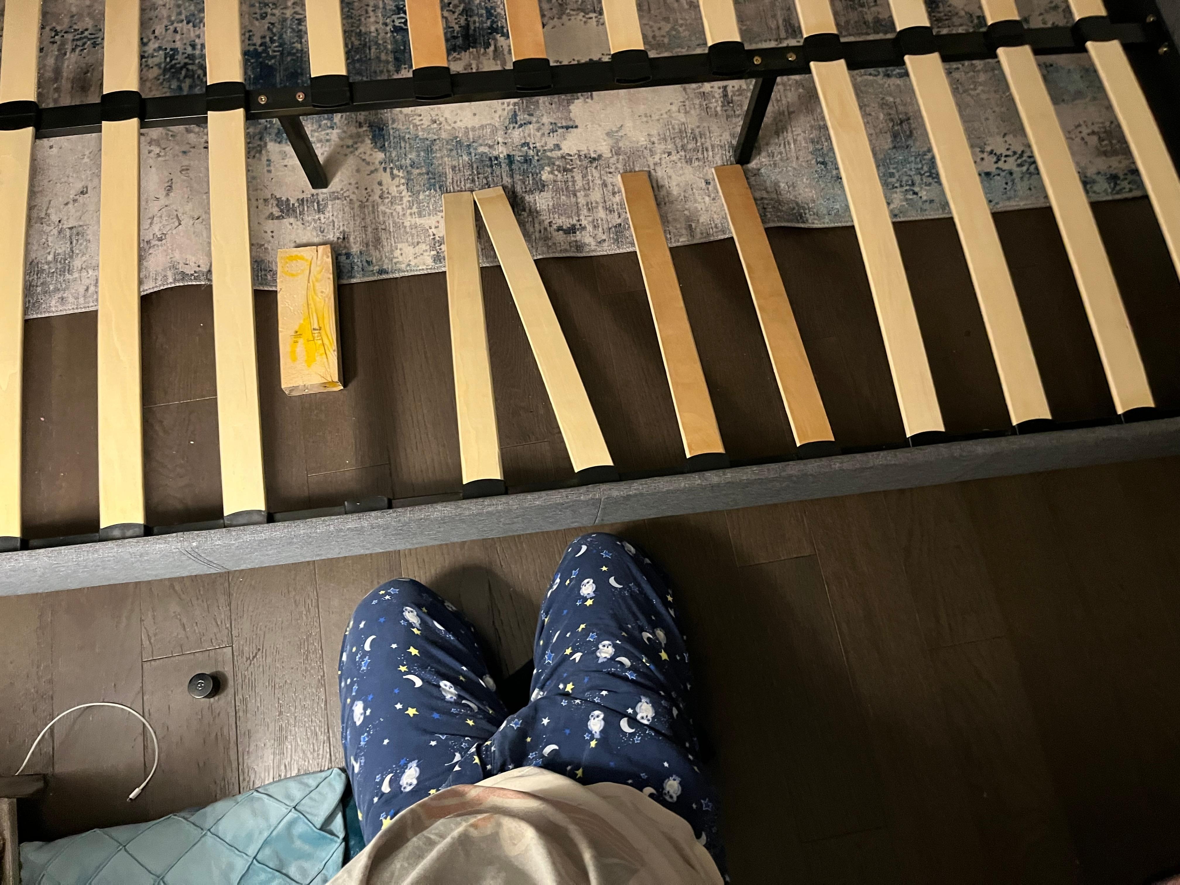 King bed mid-repair the black metal legs are not attached to the rail anymore - the 2x4 has been added to prop up where the missing slat would be