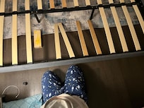 King bed mid-repair the black metal legs are not attached to the rail anymore - the 2x4 has been added to prop up where the missing slat would be