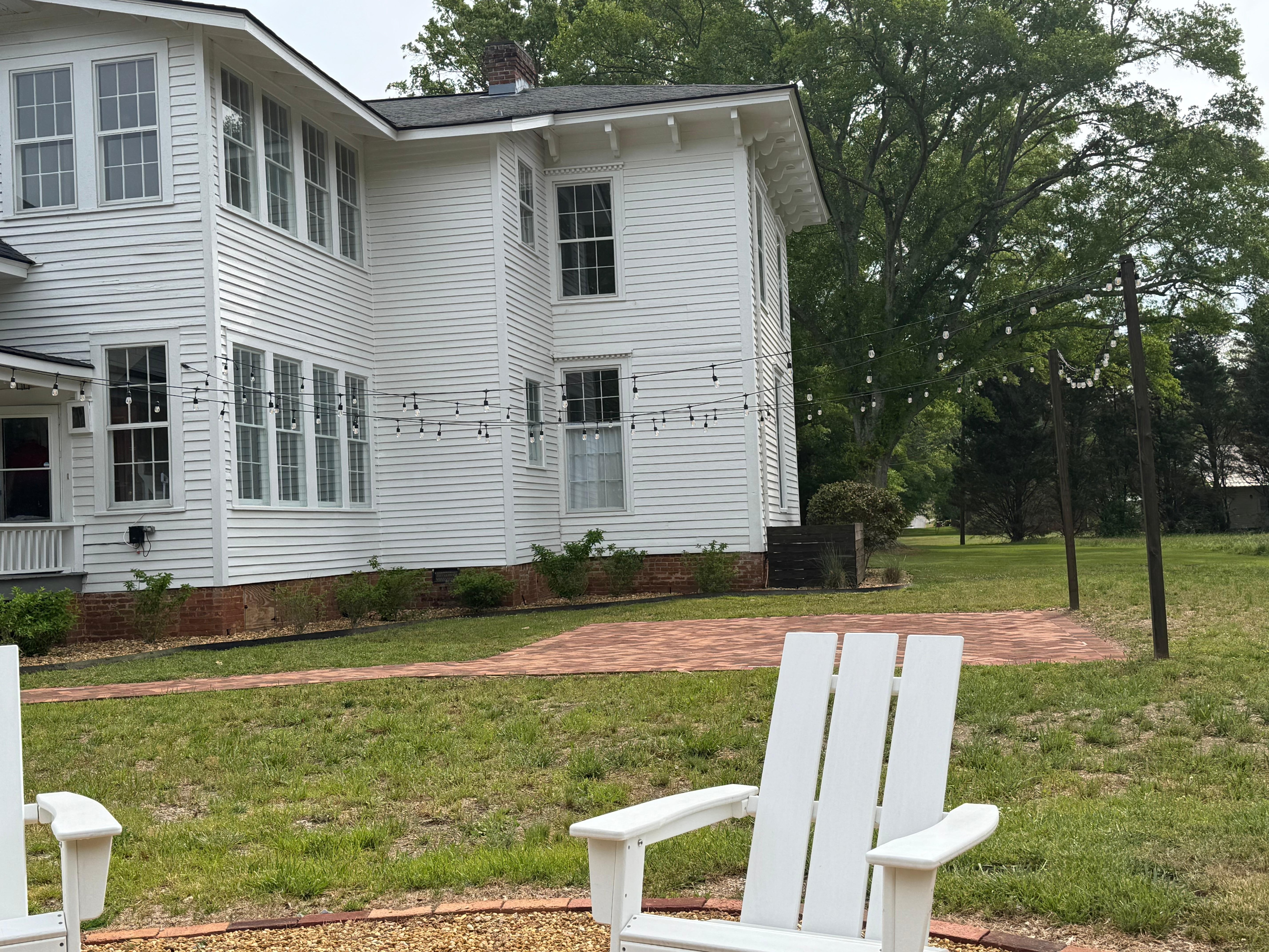 Firepit with grill top and chairs. A brick patio ( or dancefloor) under the lights.