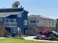 The smaller home on the right has a sweeping view of the beach and grassy park where people and their pets frolic and relax.