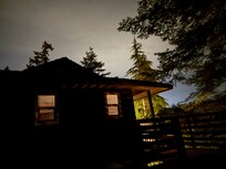 Late evening view of the house from the deck with the fire table and hot tub.