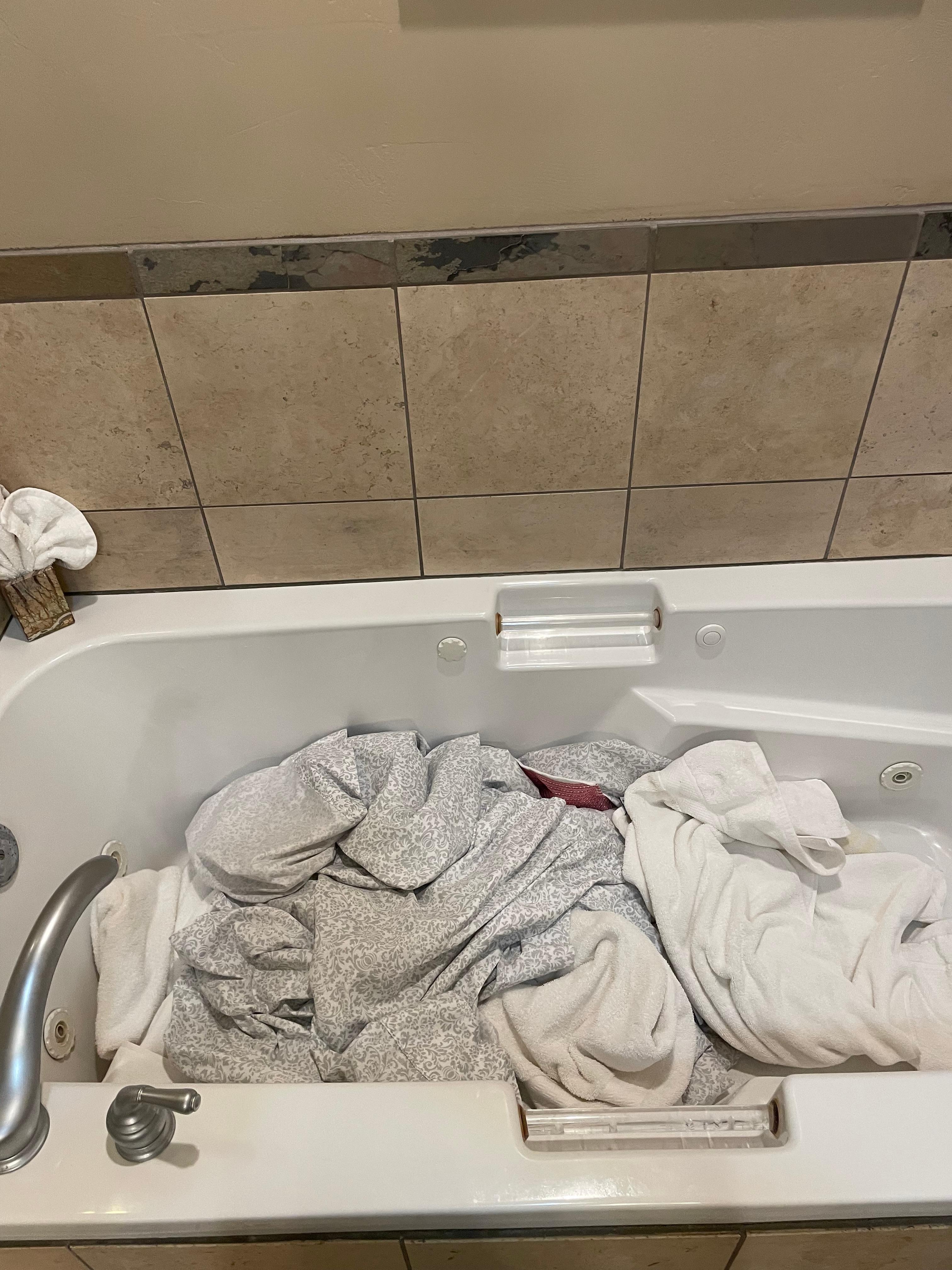 Dirty towels and bedding in the master bedroom bath tub 