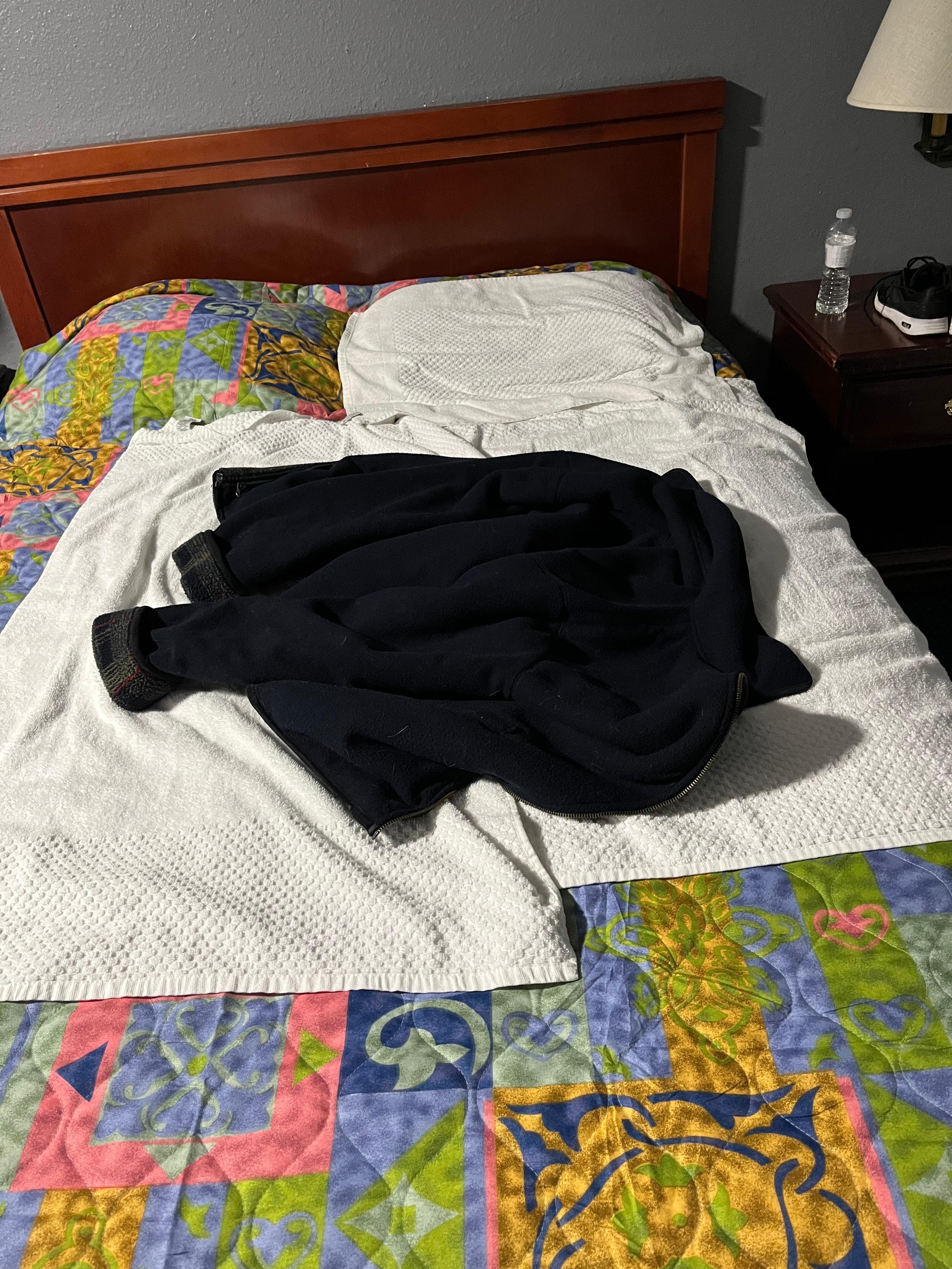 Towels on bedspread with coat for blanket
