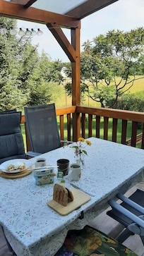 Sehr schöne überdachte Terasse mit einem weiten Blich auf Wiese, Wald und See.