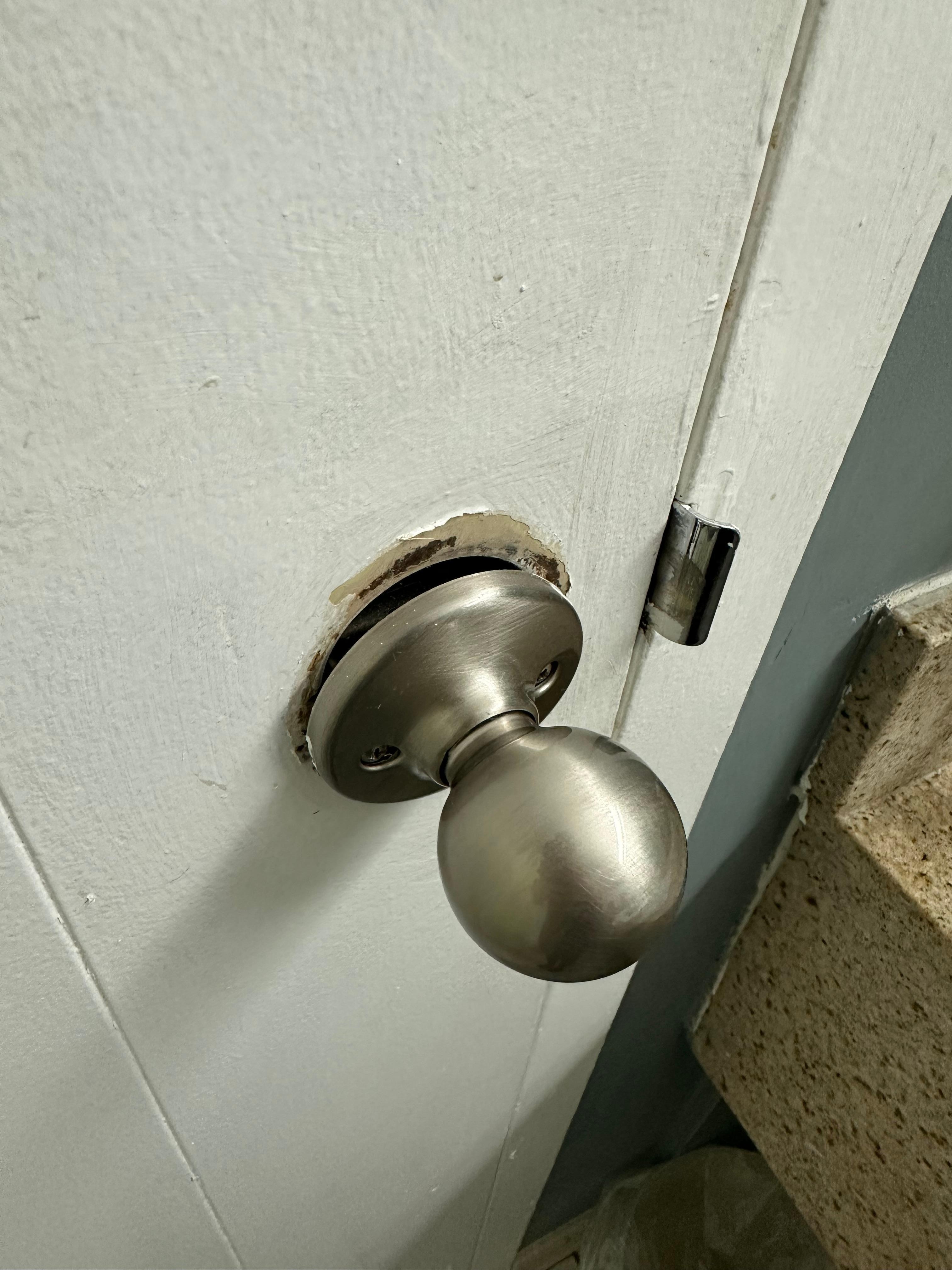 Bathroom door knob almost falling out of door