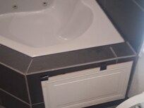A busted cabinet door covering a hole in Jacuzzi tub with tape