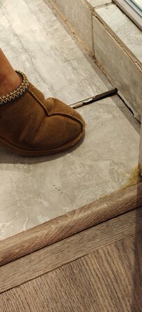 Floor that is collapsing and letting water in between broken tiles.