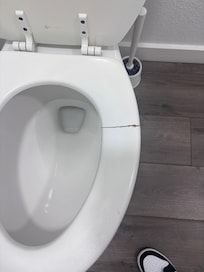 Cracked toilet seat that can cause pinching and cuts