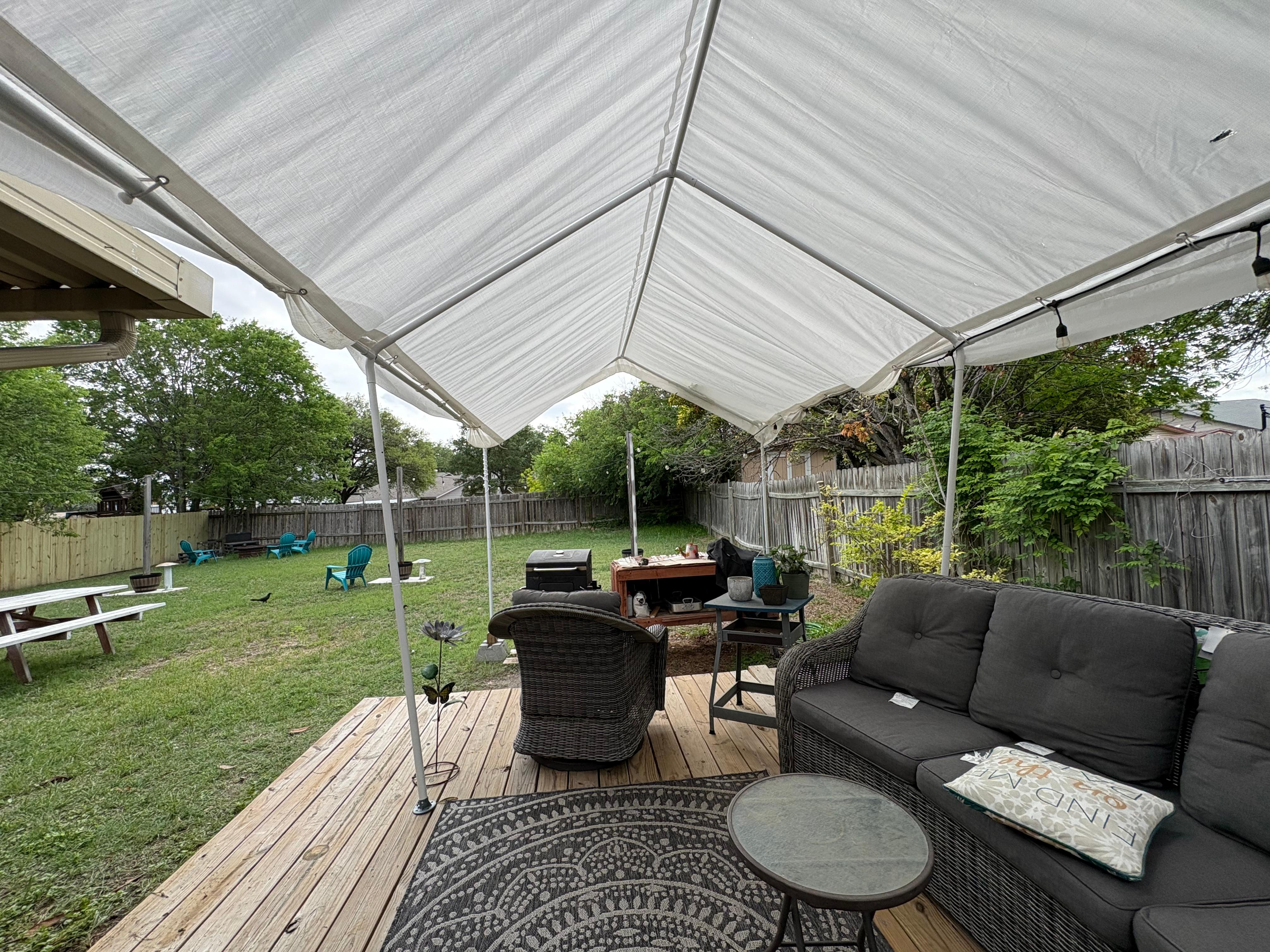 Picnic table to the left and fire pit in corner by blue chairs 