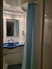 Bloc salle de bain avec douche, lavabo et toilettes.
Distributeur de savon eco responsable