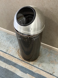 old rusted trash can with old stained carpet