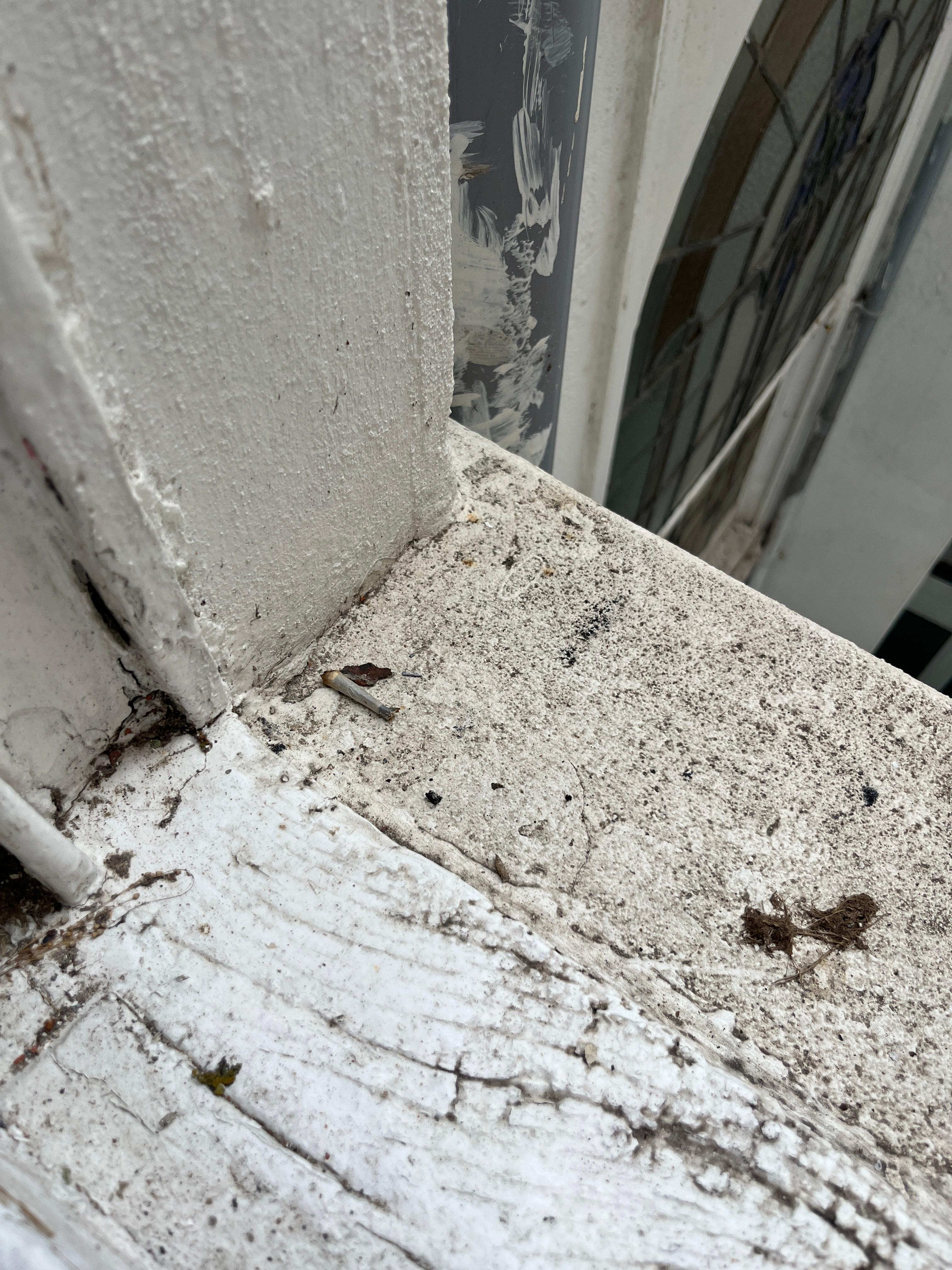 Cigarette butts on the rotting window cile