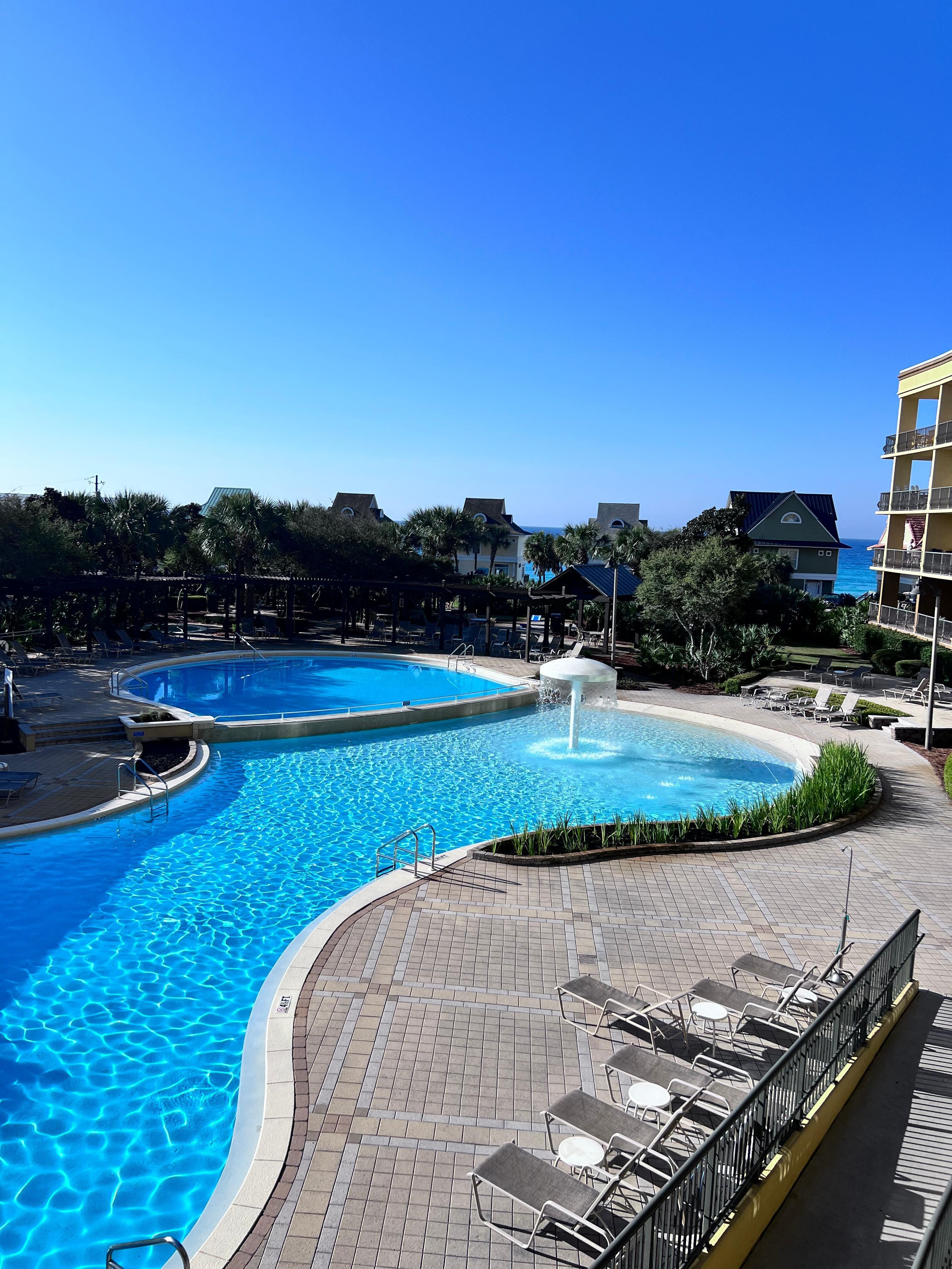 The pool area from the balcony of the room with a little peak of the ocean in the background.